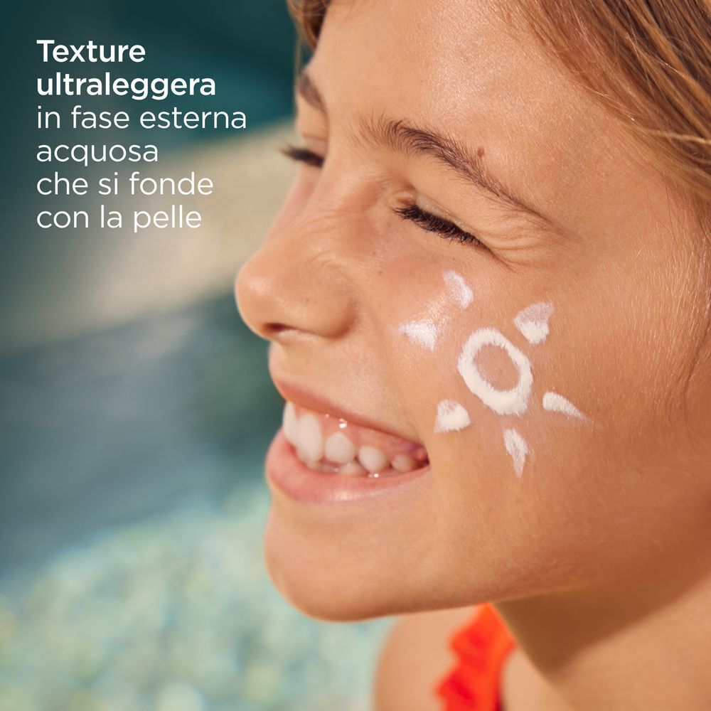Bambina con un simbolo di sole sulla guancia, che mostra la texture ultraleggera della crema solare.
