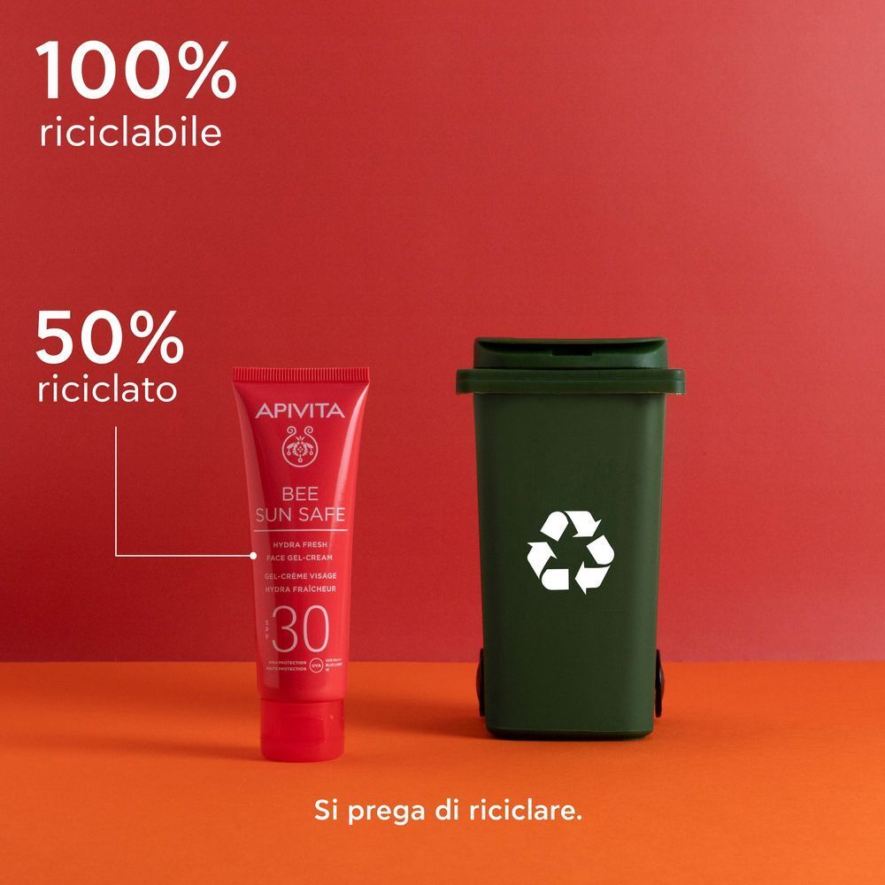 Tubo rosso APIVITA Bee Sun Safe Hydra Fresh Face Gel-Cream SPF 30 accanto a un bidone verde con simbolo riciclo.