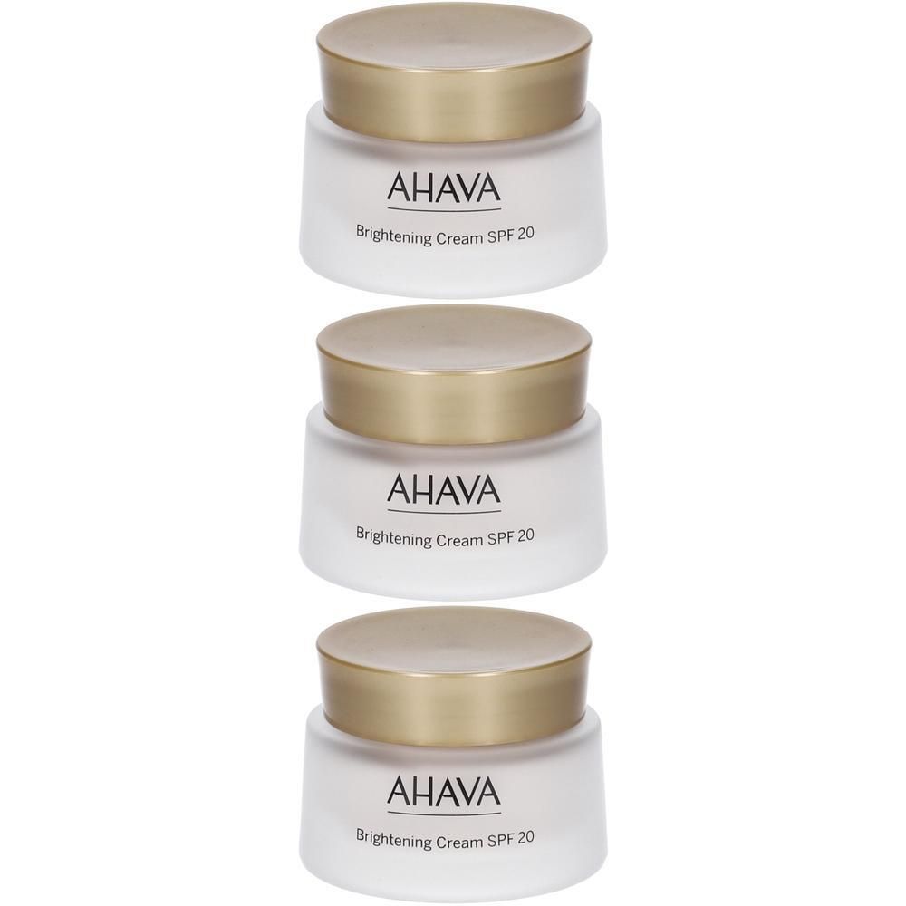 Tre vasetti bianchi AHAVA Brightening Cream SPF 20 con tappi dorati.