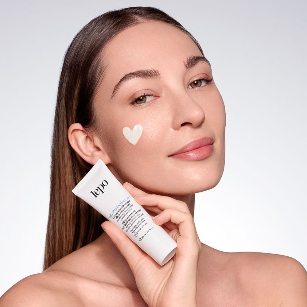 Donna con crema viso LEPO Daily Protection 50+ SPF 50+ sulla guancia.