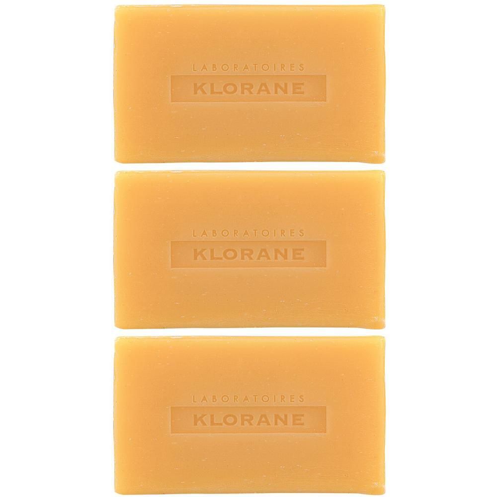 Tre saponette Klorane rettangolari color arancio con logo in rilievo.