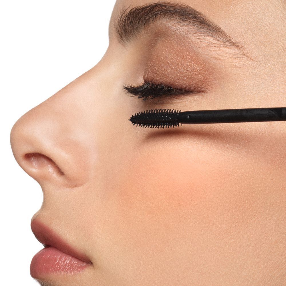 Primo piano di una donna che si applica il mascara sulle ciglia. Applicatore nero.