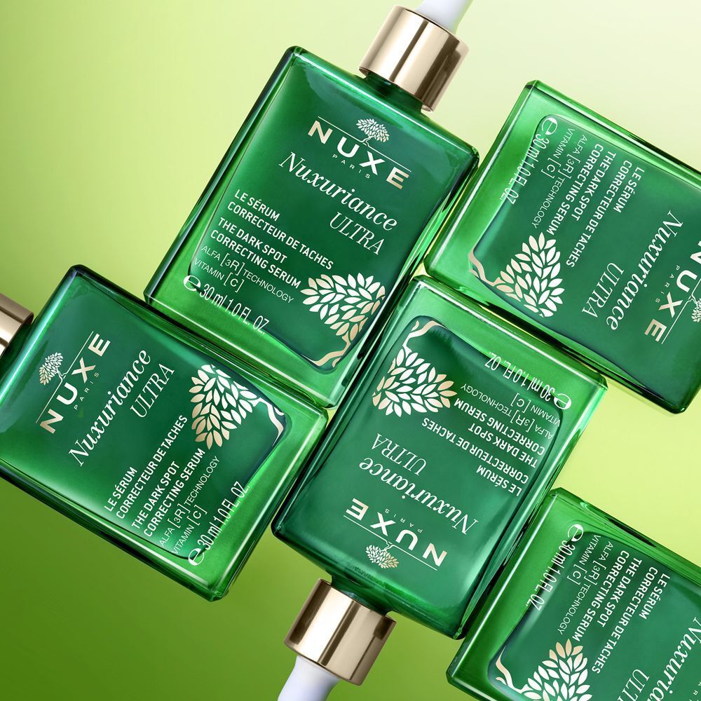 Molti flaconi in vetro verde Nuxe Nuxuriance Ultra Siero disposti diagonalmente.