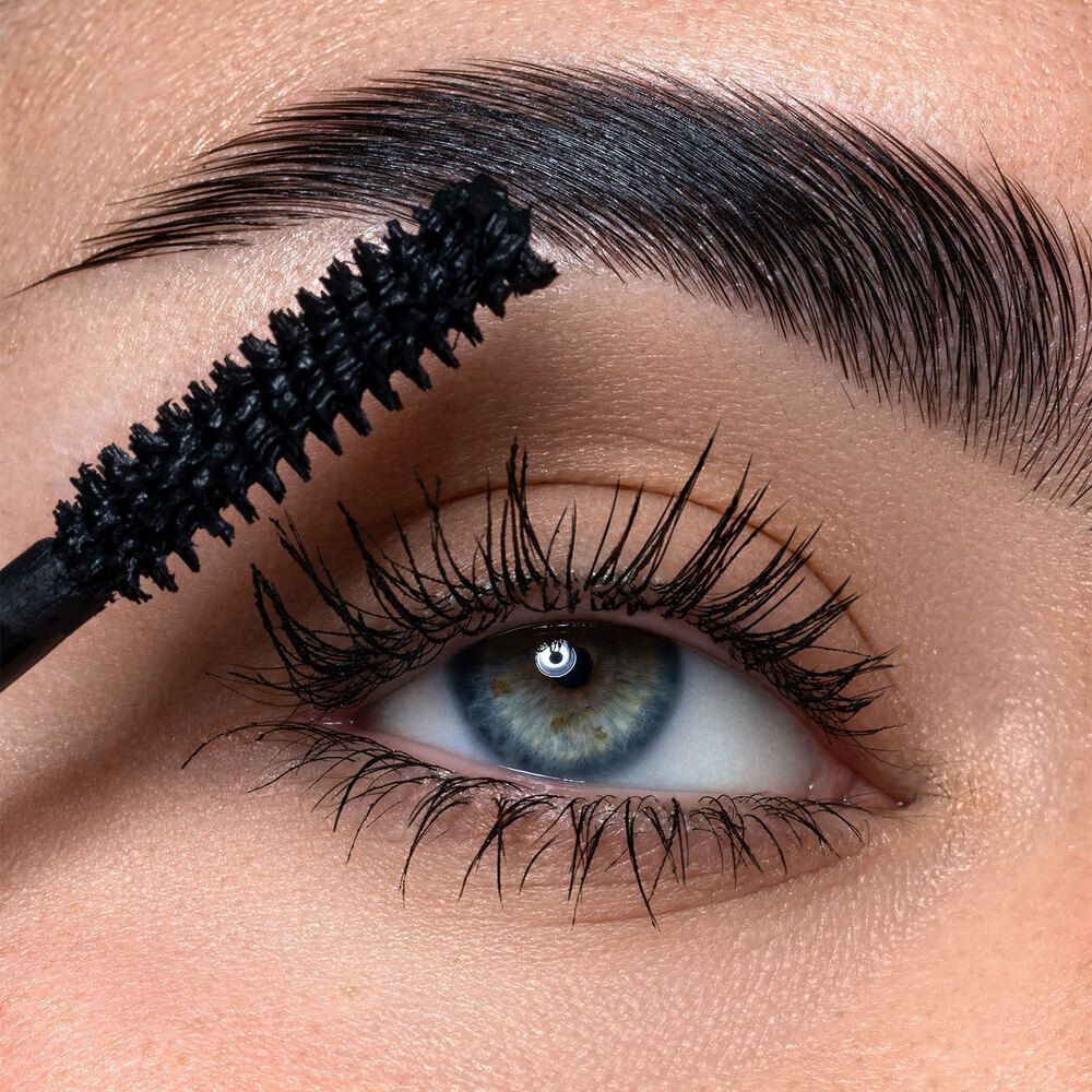 Un applicatore di mascara nero spazzola le ciglia di una persona.