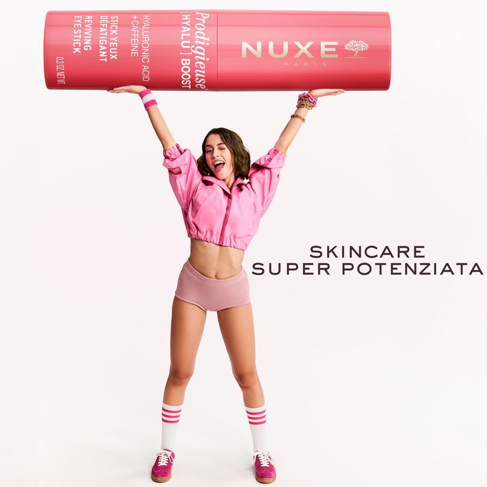 Una donna solleva uno stick contorno occhi Nuxe Prodigieuse [Hyalu] Boost sopra la testa.