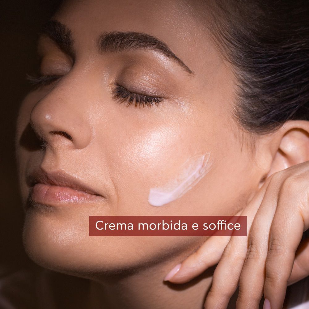 Crema sulla guancia di una donna, crema notte Apivita Beevine Elixir.