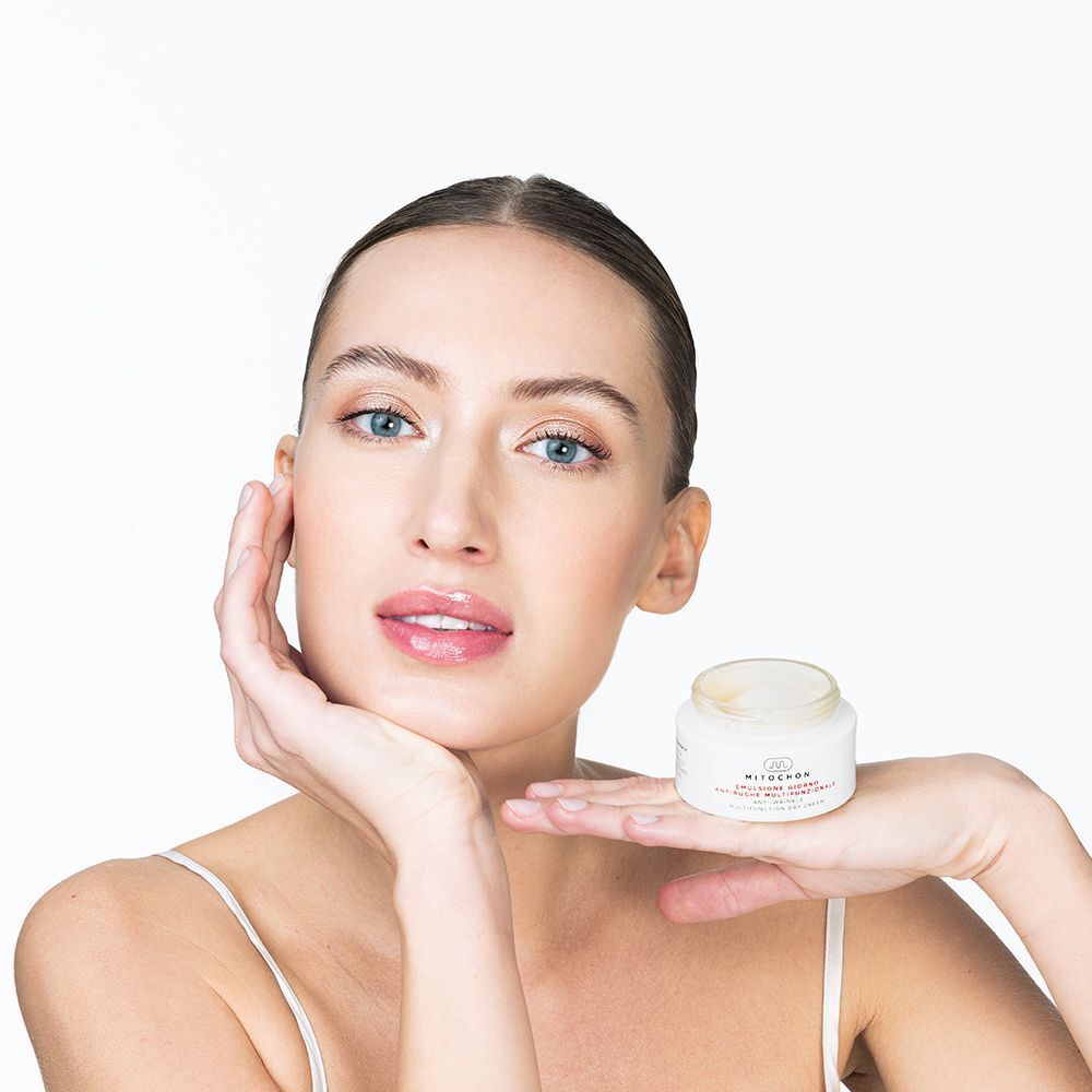 Donna con vasetto di crema giorno Mitochon in mano, con focus sul prodotto.