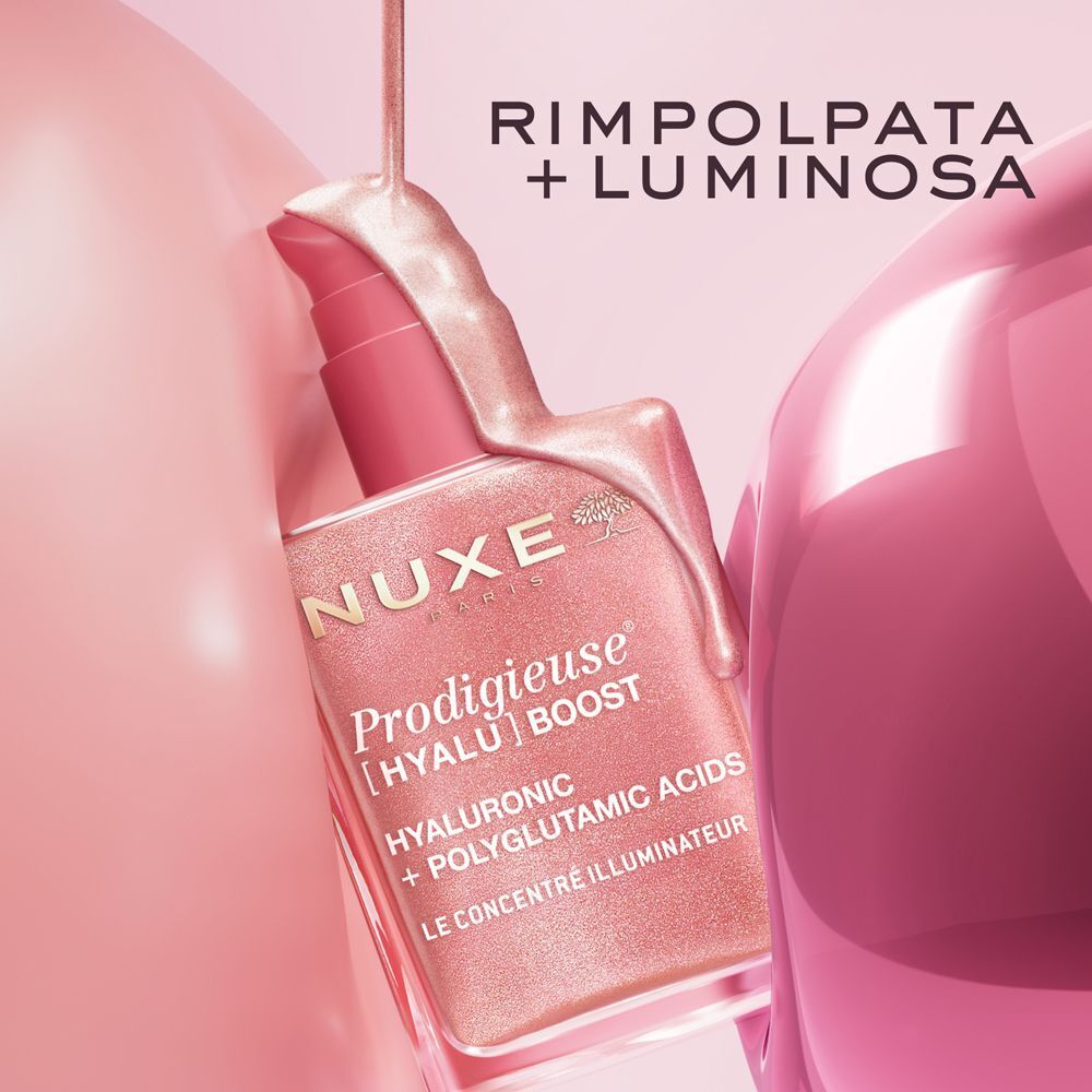 Flacone Nuxe Prodigieuse [Hyalu] Boost circondato da elementi rosa, texture scintillante.