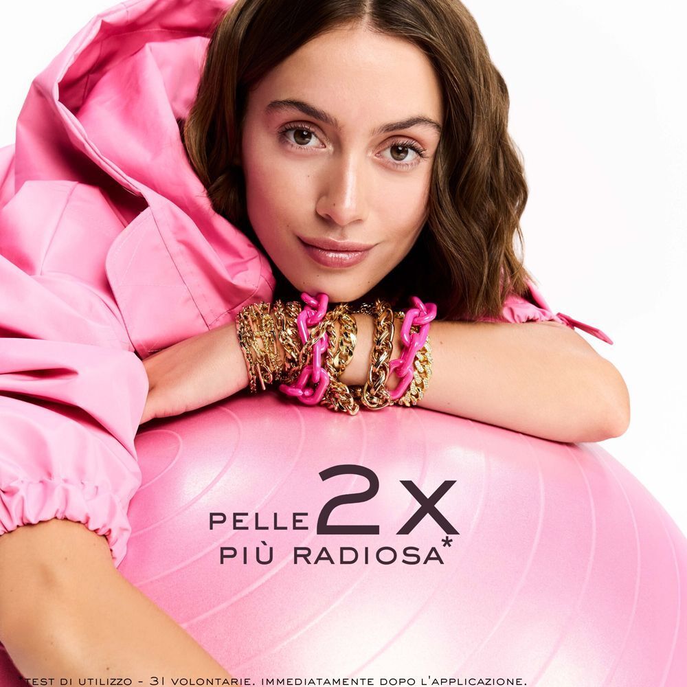 Primo piano di una donna con gioielli. Testo: Pelle 2x più radiosa.