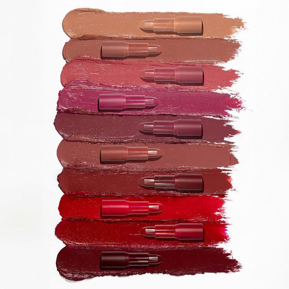 Dieci rossetti in varie tonalità di rosso, rosa e nude, applicati come campioni su sfondo bianco.
