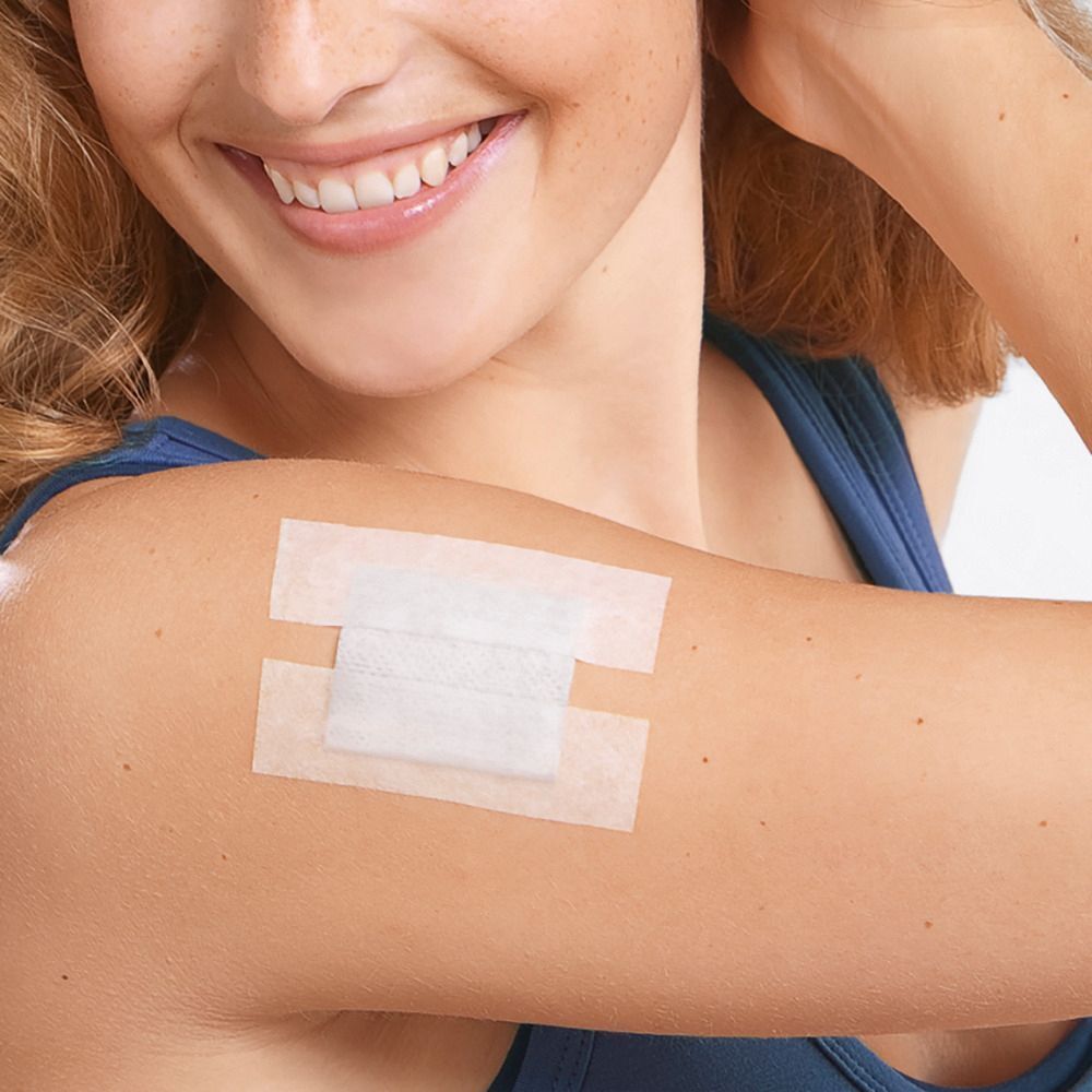 Una medicazione applicata sulla pelle con due strisce adesive, bianca.