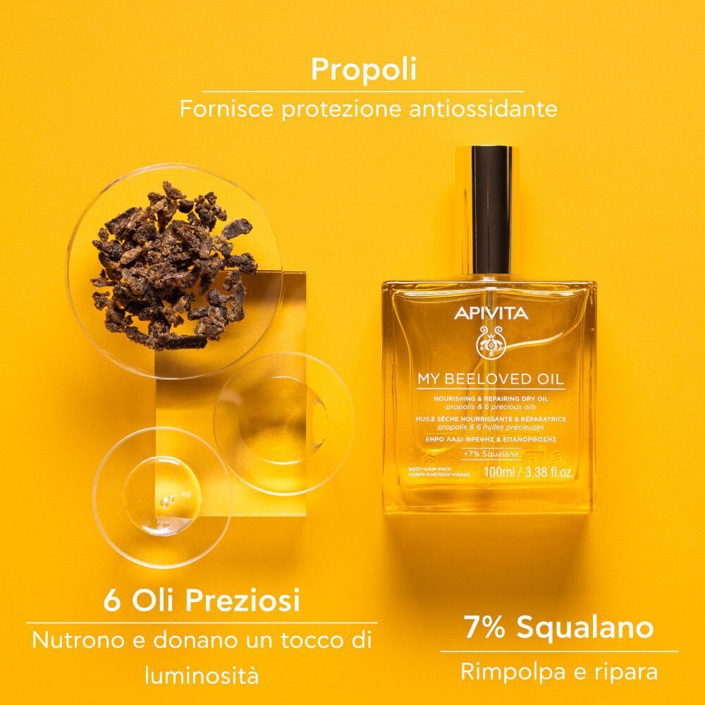 Flacone di APIVITA My Beeloved Oil accanto a pezzi di propoli e bicchieri con oli. Testo: 'Propoli', '6 Oli Preziosi', '7% Squalano'.