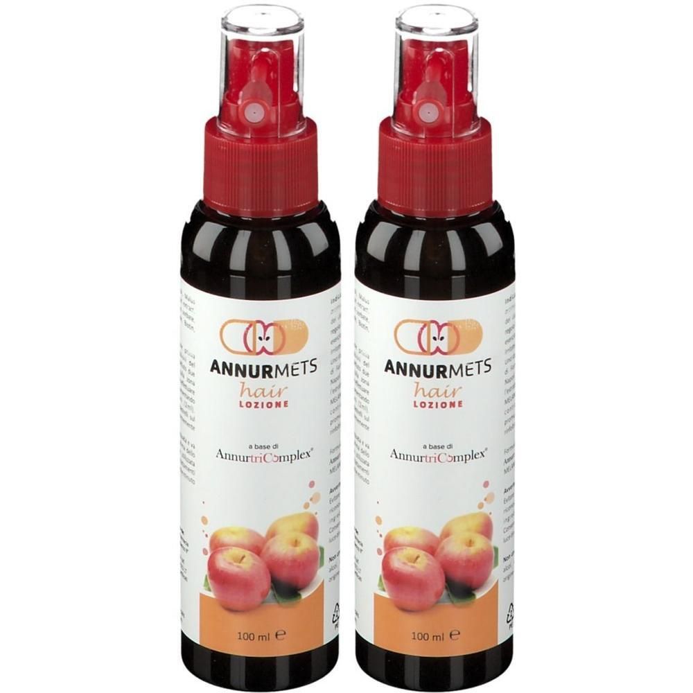Due flaconi di lozione per capelli Annurmets con spruzzatore e tappo rossi. Flaconi scuri con etichetta raffigurante mele e testo. 100 ml.