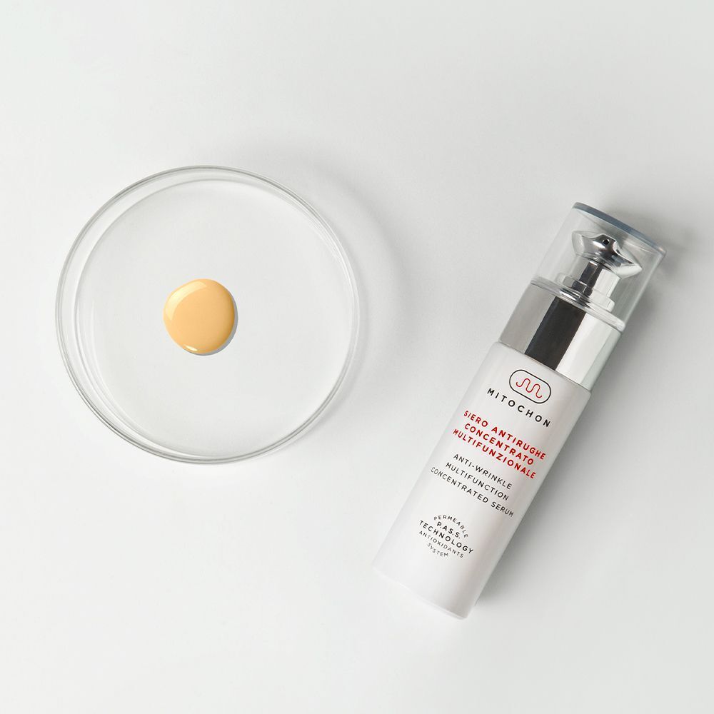 Flacone dispenser accanto a capsula Petri con siero, Mitochon Siero Concentrato Anti-Rughe Multifunzionale.