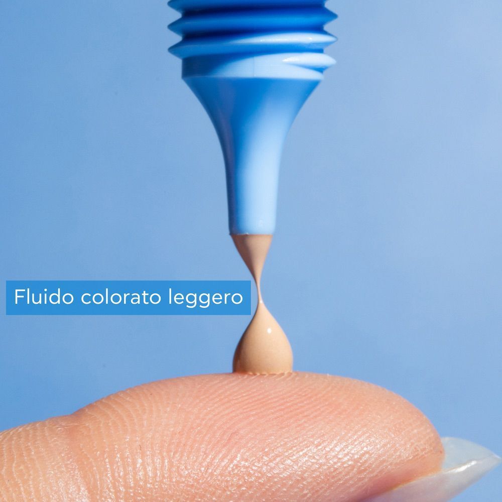 Goccia di crema fluida colorata Apivita Aqua Beelicious SPF 30 su un dito.