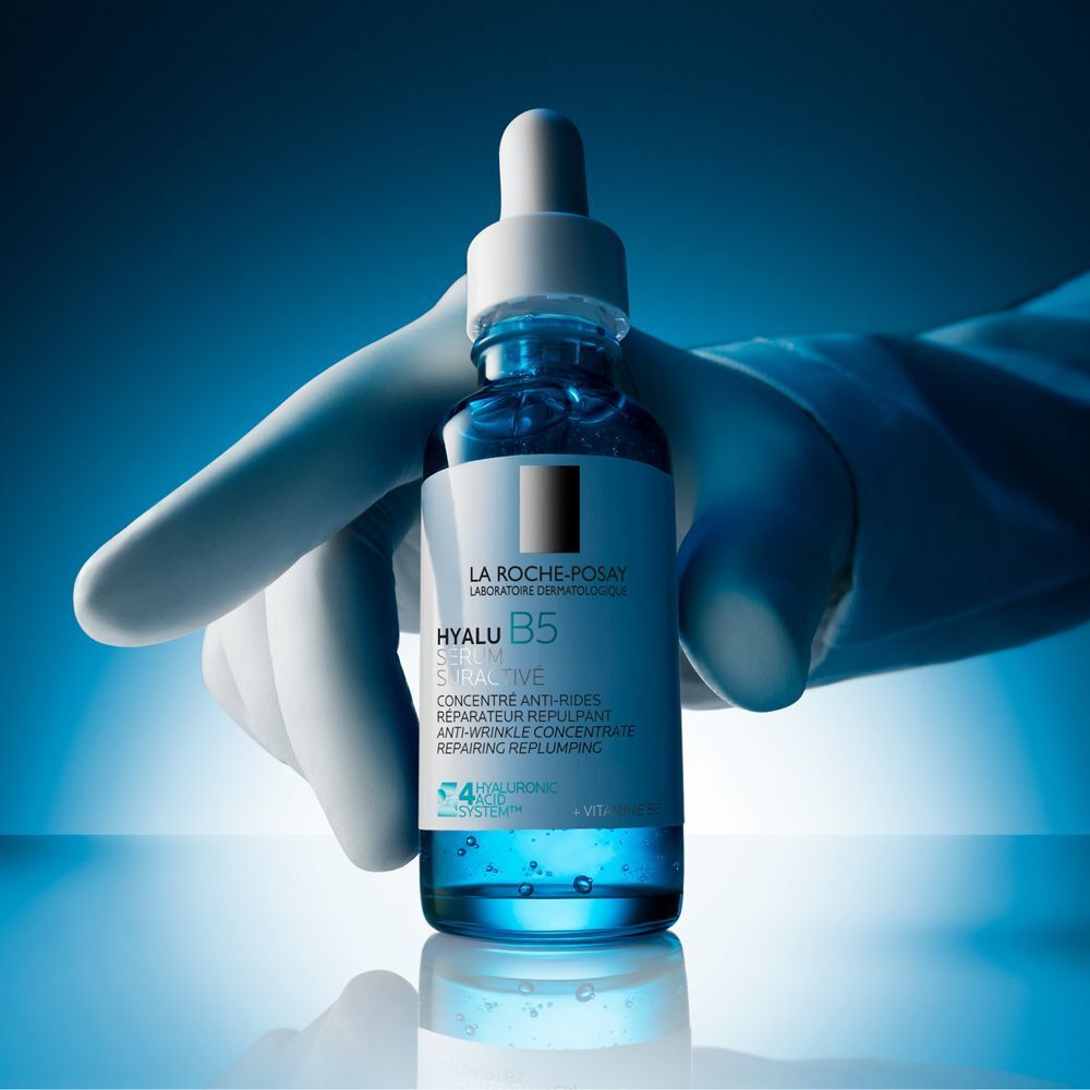 Mano con guanto tiene flacone di siero La Roche-Posay Hyalu B5.