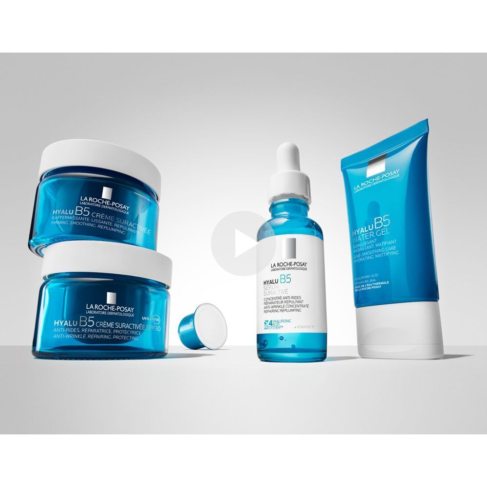 Flacone siero, vasetto crema e tubo La Roche-Posay Hyalu B5 su sfondo blu.
