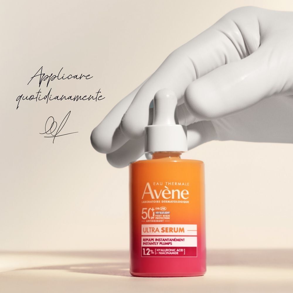 Mano guantata tiene Eau Thermale Avène Ultra Siero SPF50+. Testo: 'Applicare quotidianamente'.