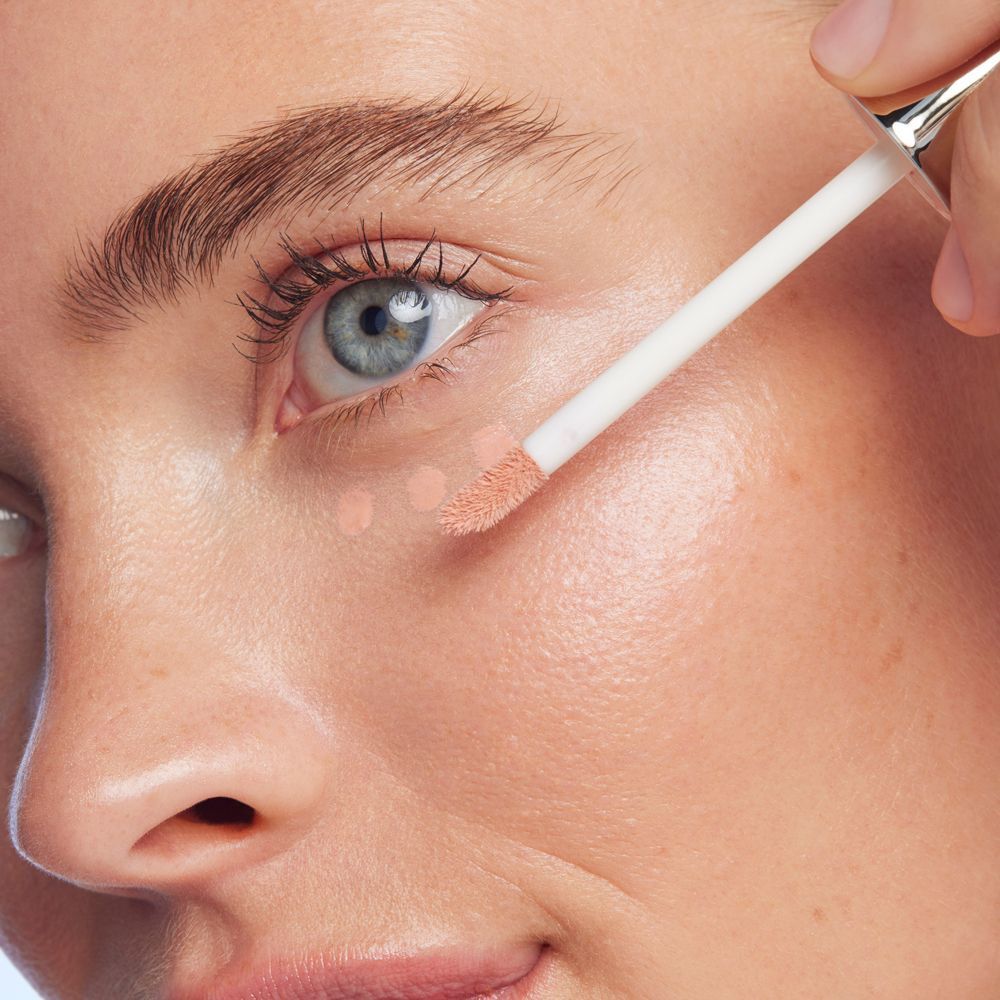 Una donna applica il Nuxe Merveillance Lift Siero Contorno Occhi Illuminante sotto l'occhio con l'applicatore.