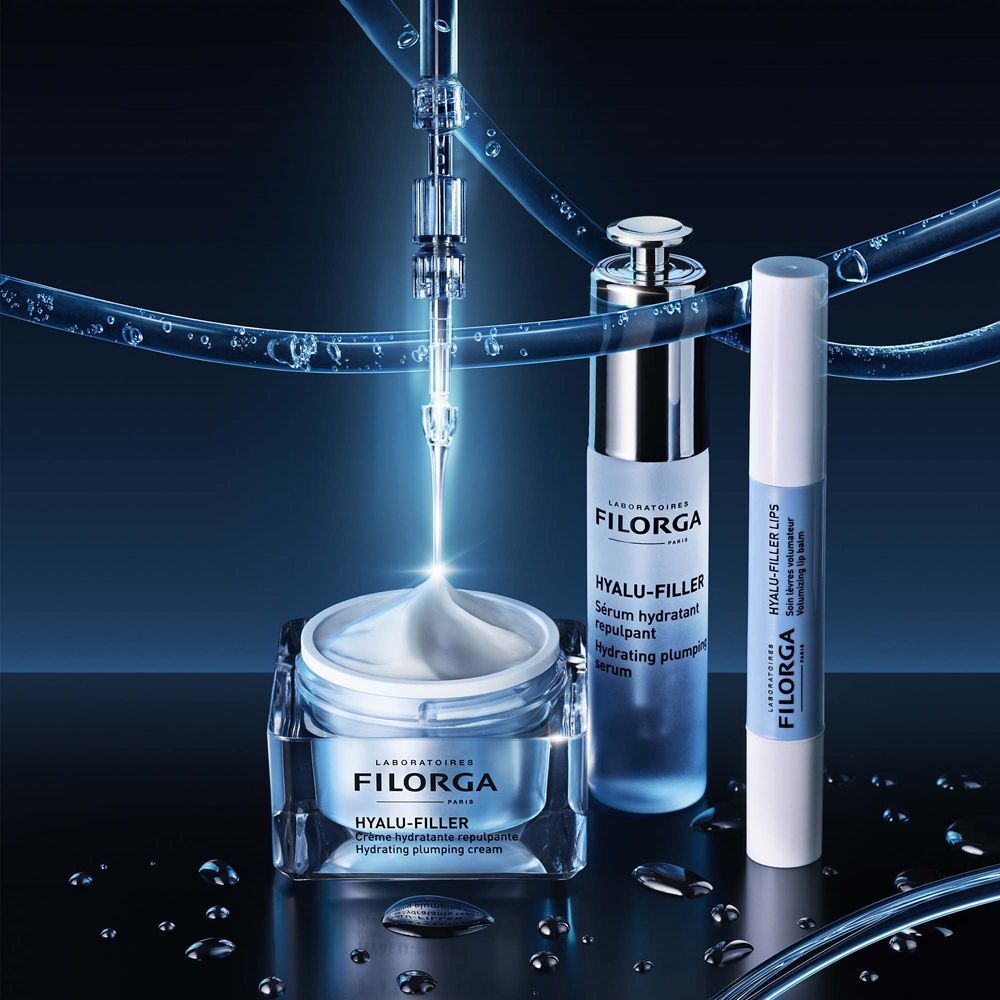 Crema idratante, siero e balsamo labbra Filorga Hyalu-Filler in un ambiente liquido blu.