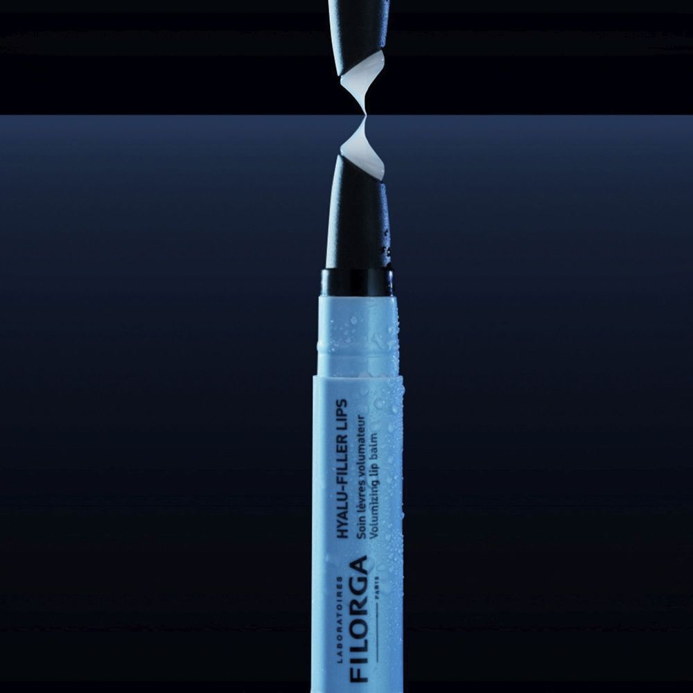 Un balsamo labbra Filorga Hyalu-Filler con applicatore in rotazione su sfondo scuro.