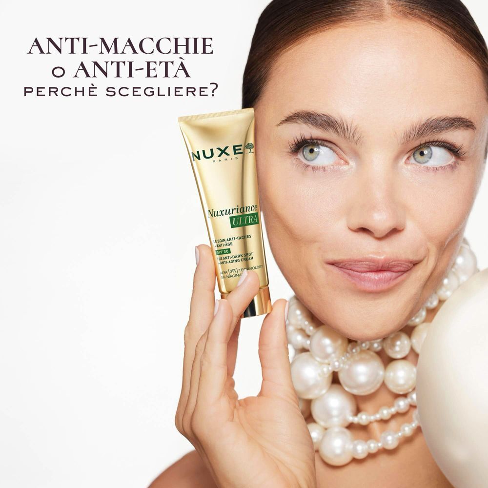 Una donna tiene un tubo dorato di Nuxe Nuxuriance Ultra Crema Anti-Età SPF 30.
