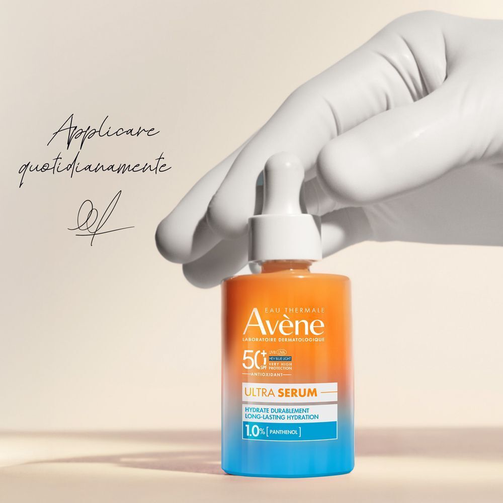 Mano guantata tiene flacone Eau Thermale Avène Ultra Siero SPF50+. Testo: 'Applicare quotidianamente'.