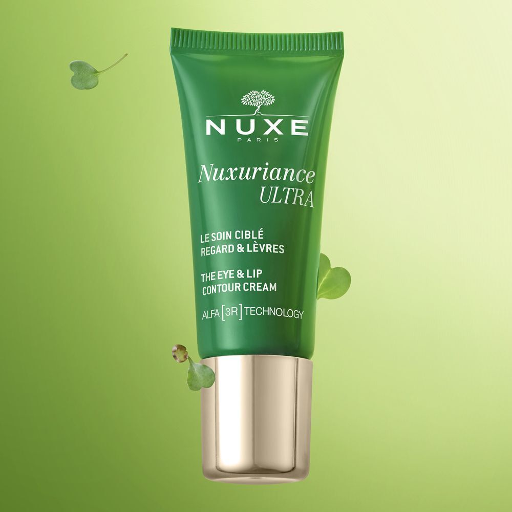 Tubo verde Nuxe Nuxuriance Ultra crema contorno occhi e labbra con tappo dorato, circondato da foglie.