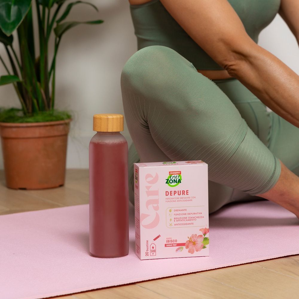 Confezione e bottiglia di bevanda EnerZona Care Depure su tappetino da yoga.