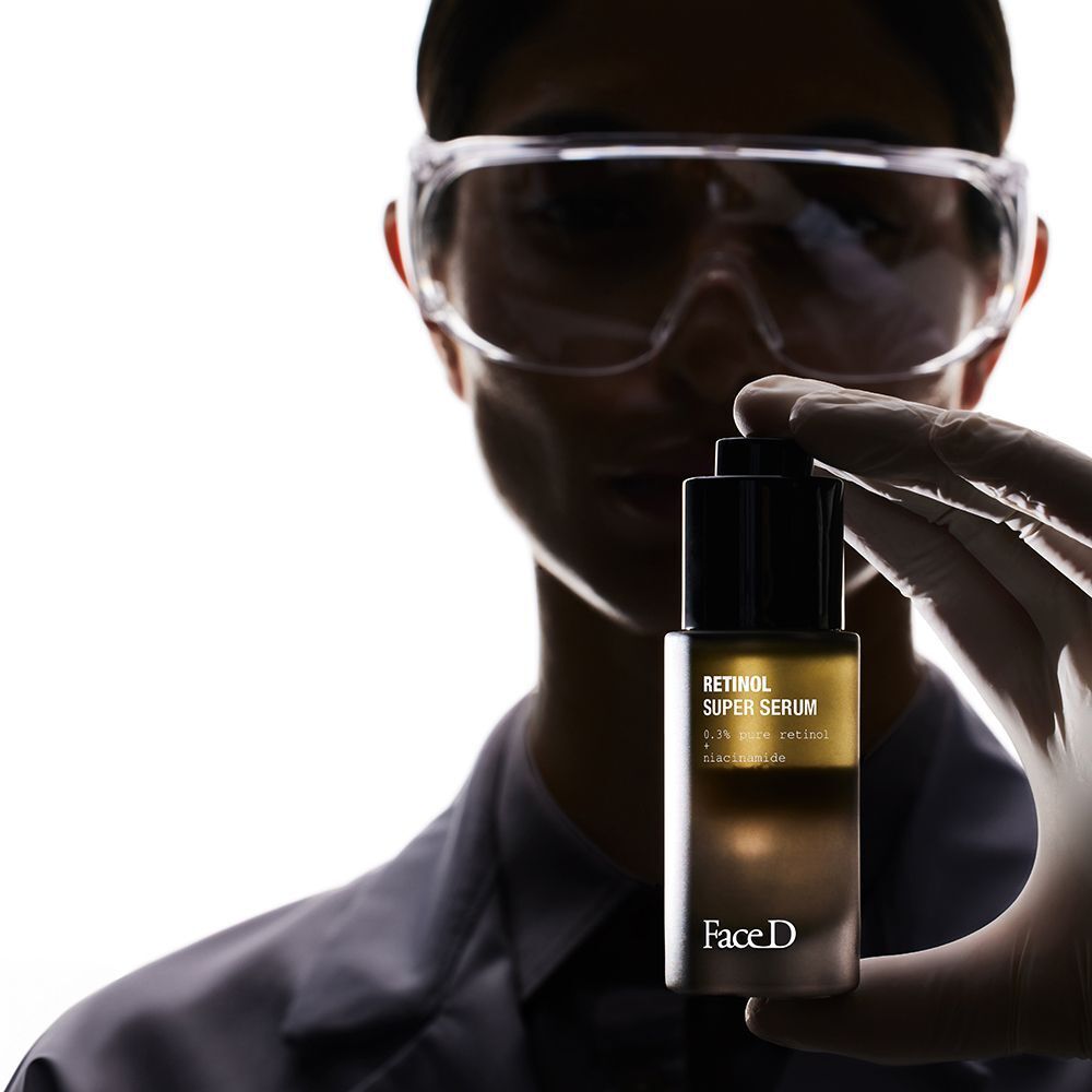 Una persona in camice da laboratorio tiene un flacone di Face D Super Siero di Retinolo.