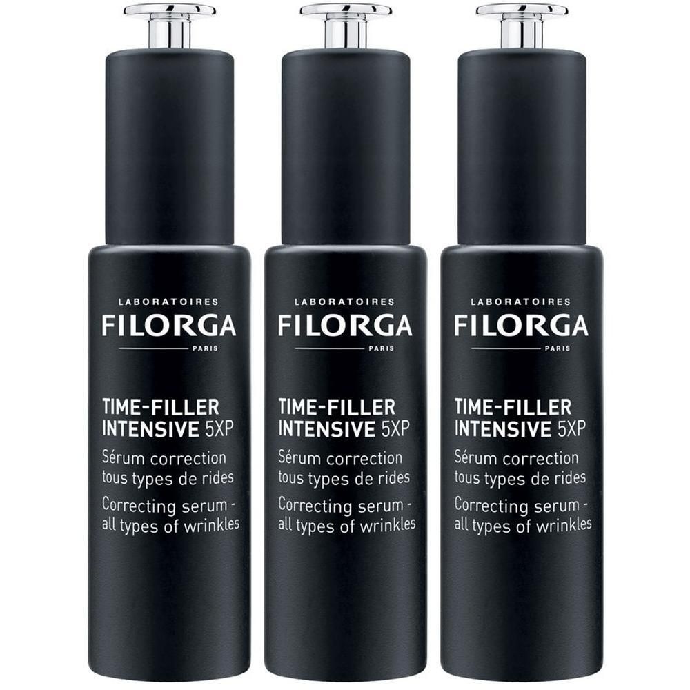 Tre flaconi neri di siero Filorga Time-Filler Intensive 5XP con tappo a pipetta.