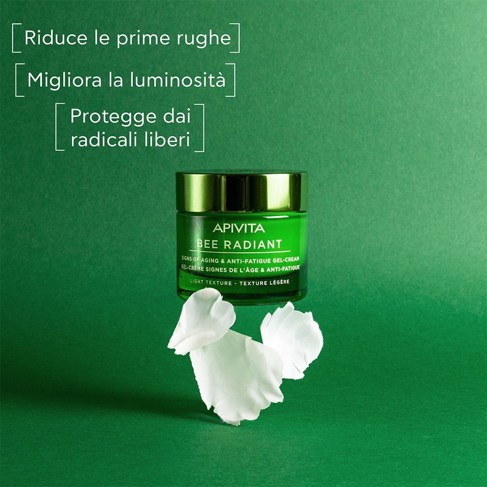 Vaso verde APIVITA BEE RADIANT crema viso con petali di fiori bianchi.