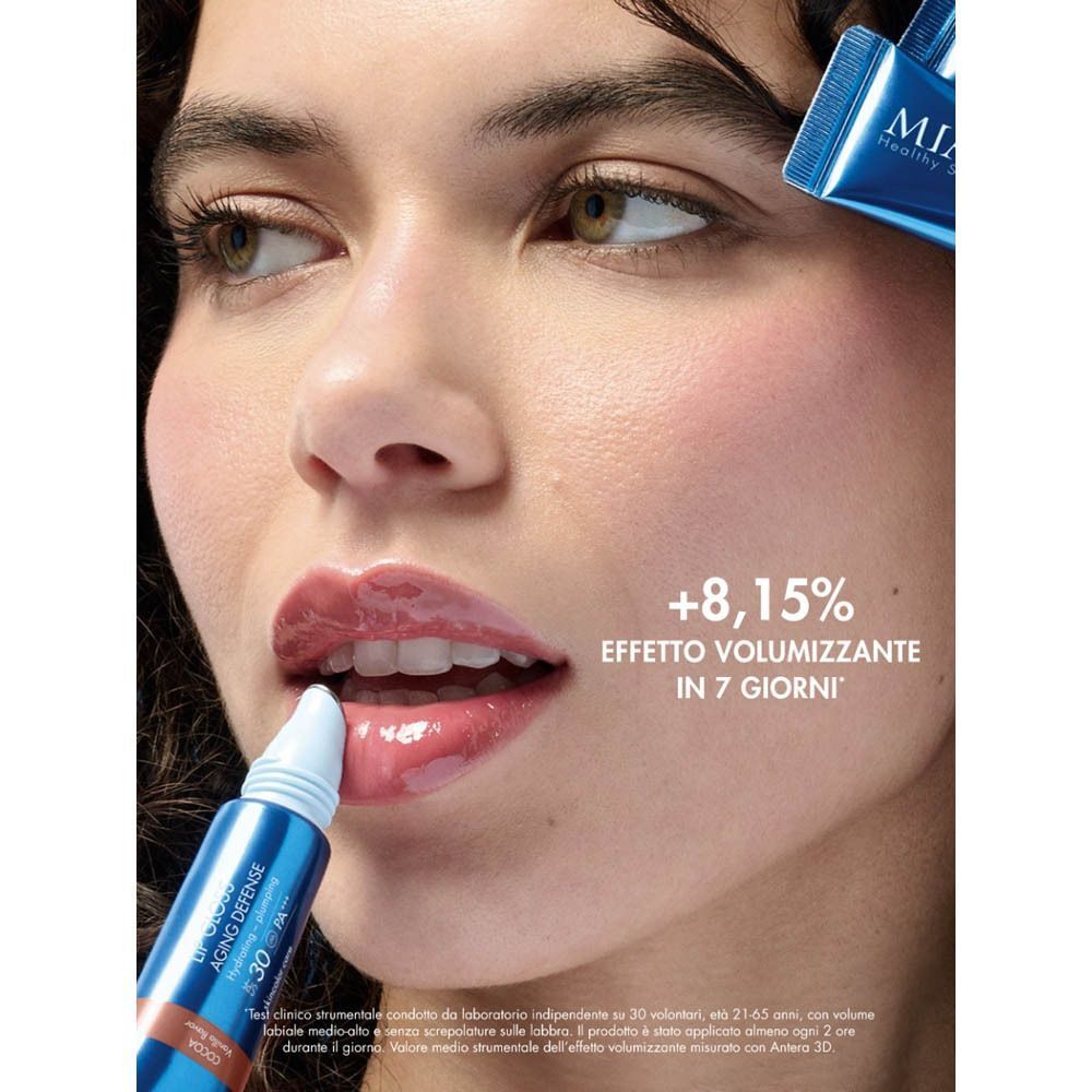 Donna con labbra lucide che usa un applicatore di balsamo labbra. Testo: +8,15% EFFETTO VOLUMIZZANTE IN 7 GIORNI.