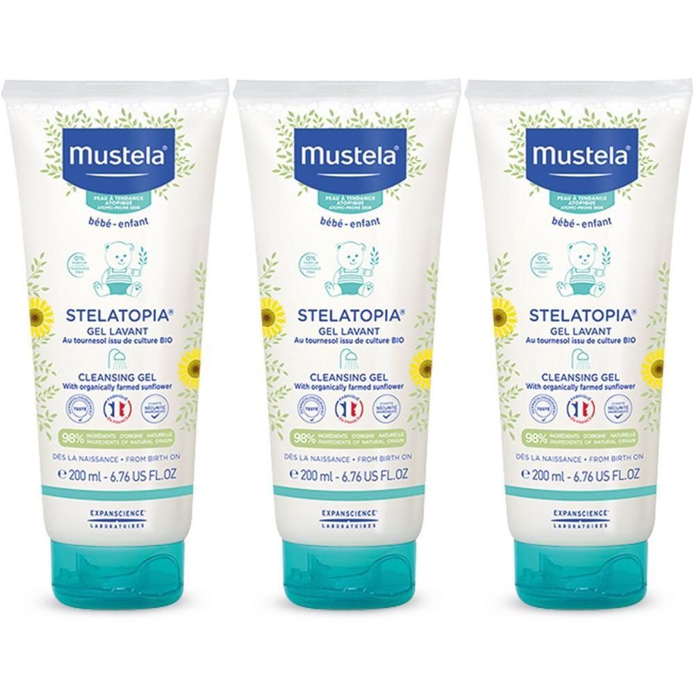 Tre flaconi di gel detergente Mustela Stelatopia con tappi turchini. Ogni flacone mostra girasoli e un orso.