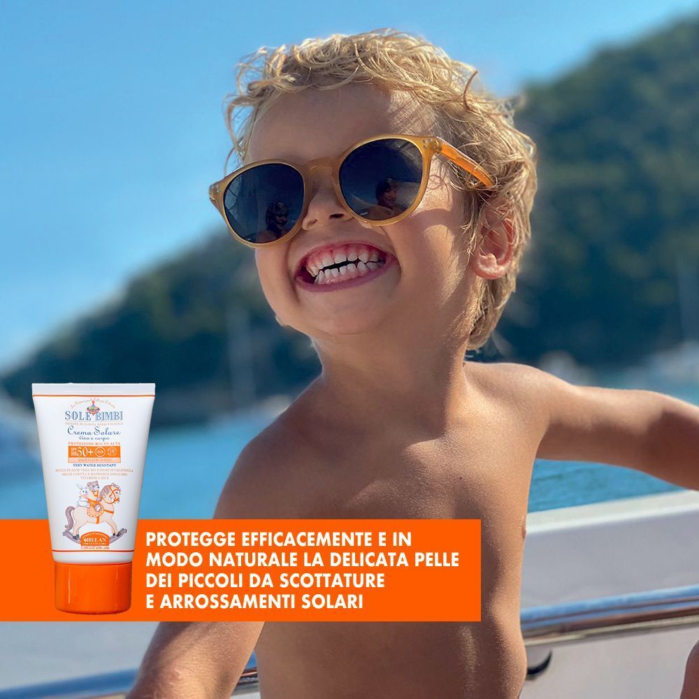 Bambino sorridente con occhiali da sole su una barca, tiene un tubetto di crema solare.