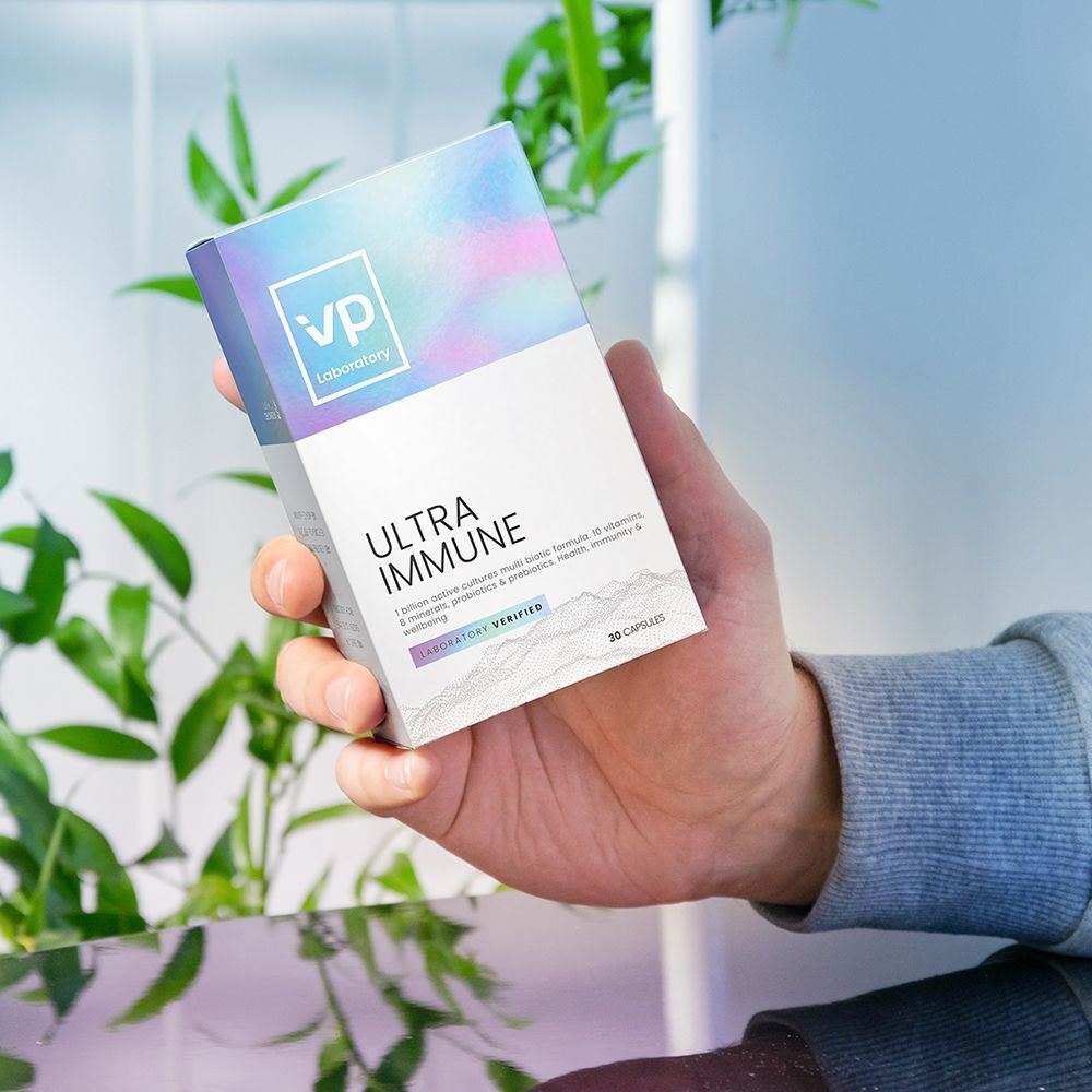 Una mano tiene una scatola VP Laboratory Ultra Immune davanti a delle piante.
