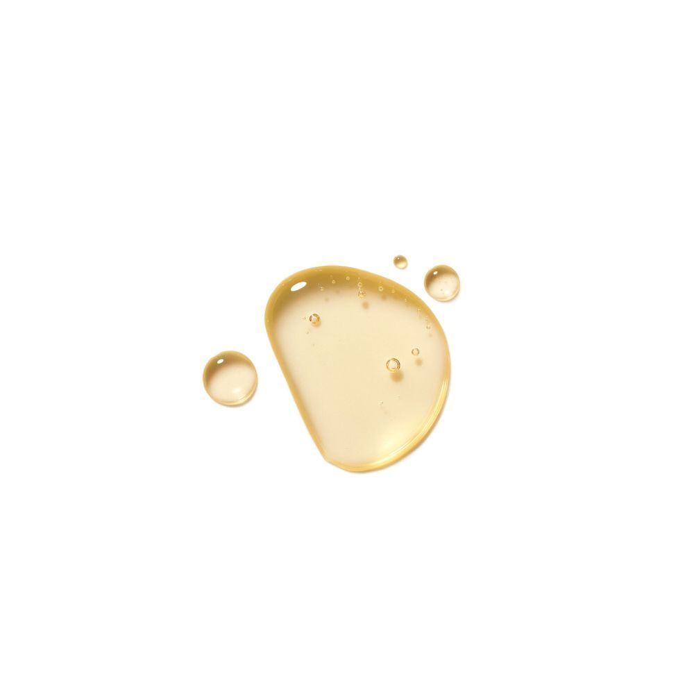 Una goccia d'olio giallo dorato con piccole bolle d'aria su sfondo bianco.