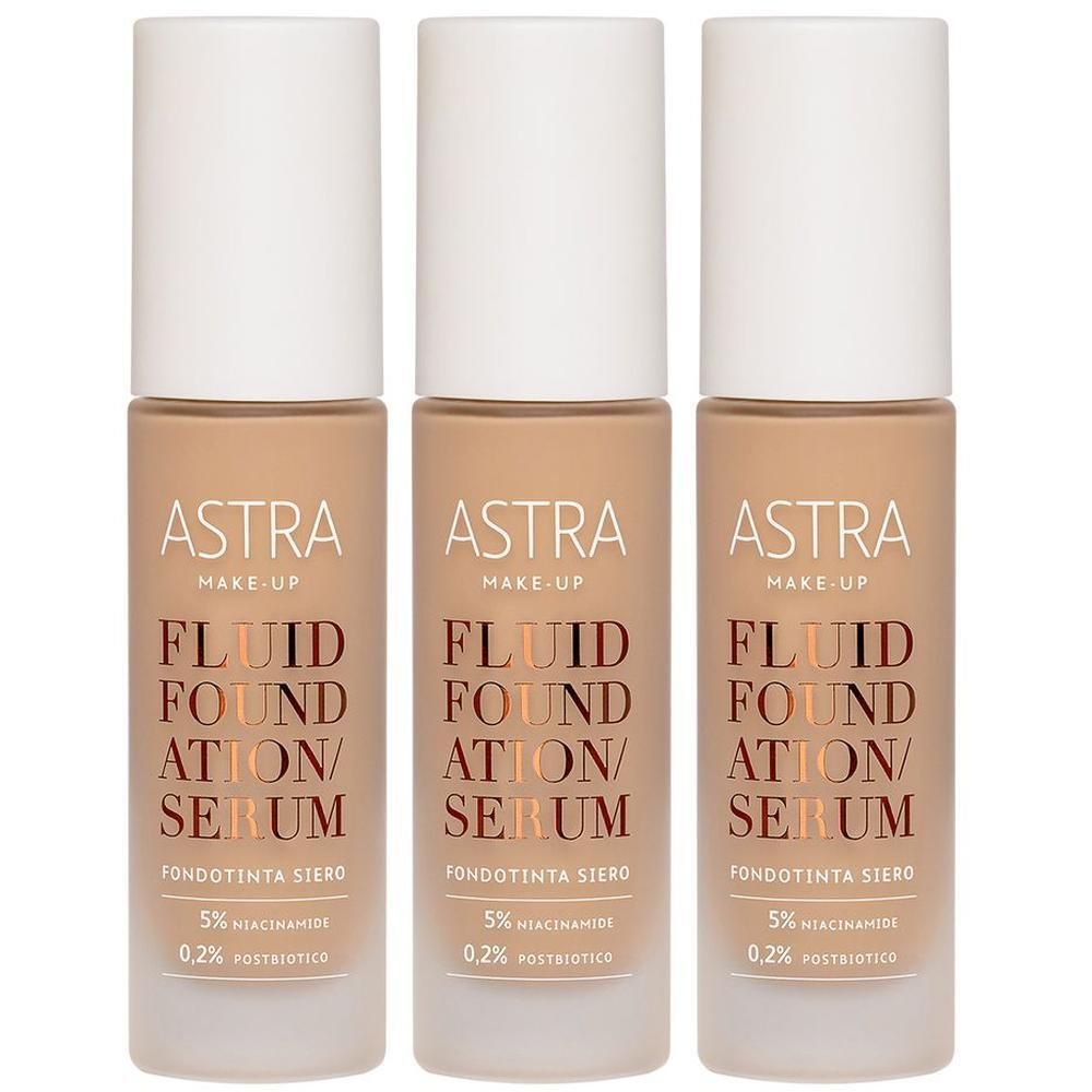 Tre flaconi Astra Make-Up Fluid Foundation/Serum color beige chiaro con tappi bianchi. Testo sui flaconi: ASTRA MAKE-UP FLUID FOUNDATION/SERUM.