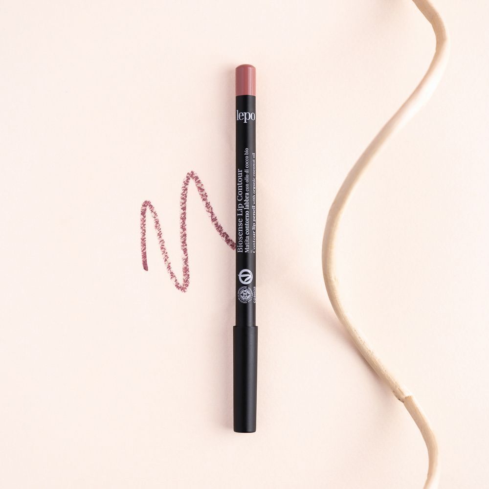 Una matita labbra color rosa con corpo nero e una linea tracciata accanto.