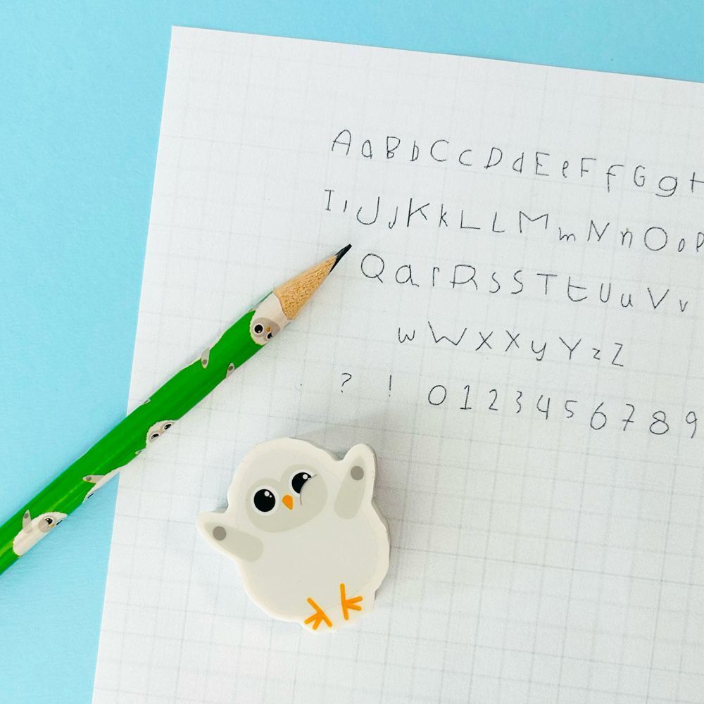 Una gomma a forma di gufo accanto a una matita ed esercizi di scrittura.