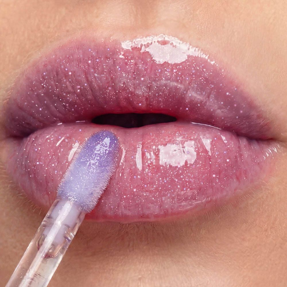 Labbra con lucidalabbra scintillante e brillante, e applicatore viola.