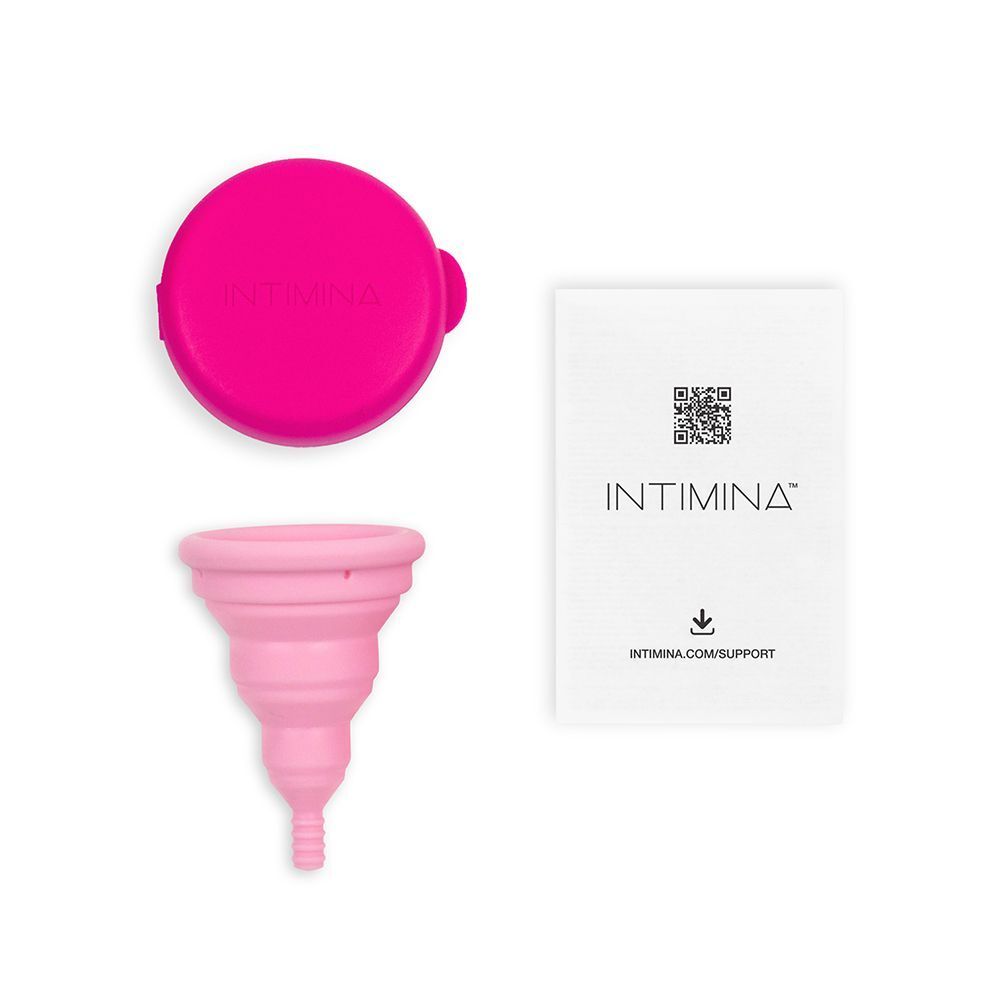 Una coppetta mestruale pieghevole rosa, un coperchio fucsias e istruzioni.