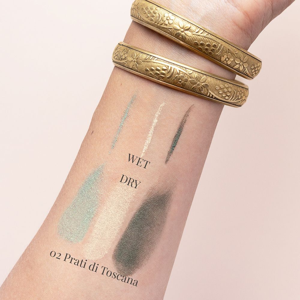 Tre campioni di ombretto sull'avambraccio: verde chiaro, beige e verde scuro. Etichettato 'WET' e 'DRY'.