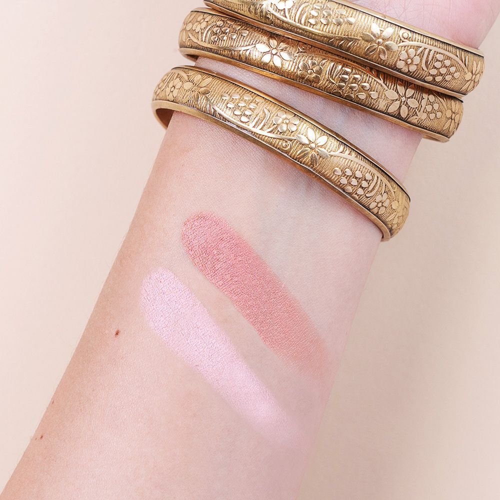 Due tonalità di fard o ombretto rosa sono applicate su un avambraccio. Bracciali dorati sono visibili.