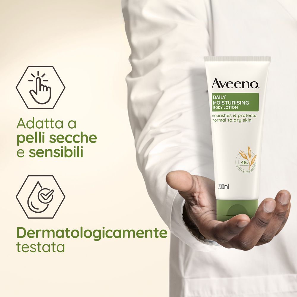 Main tenant un tube de lotion corporelle Aveeno Daily. Texte: Adatta a pelli secche e sensibili, Dermatologicamente testata.
