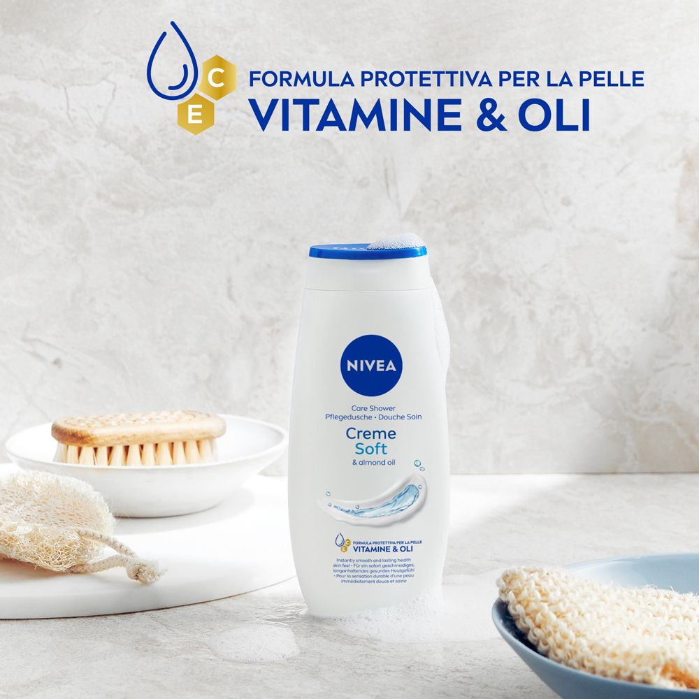 Flacone bianco con tappo blu. Testo: Creme Soft & almond oil. Con vitamine e oli. Vicino a sapone e spugna.