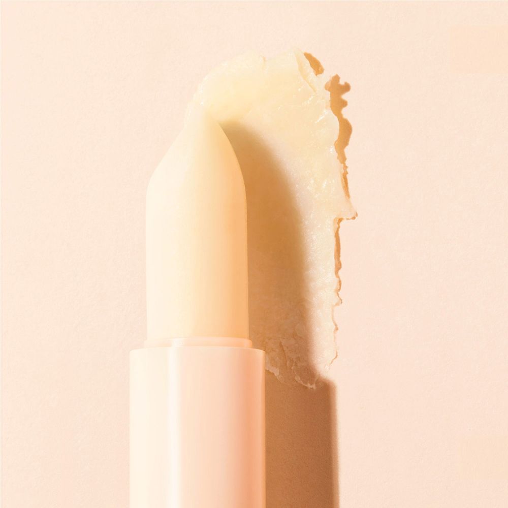 Stick labbra NUXE Rêve de Miel. Punta gialla chiara applicata. Tubetto beige. Su sfondo chiaro.