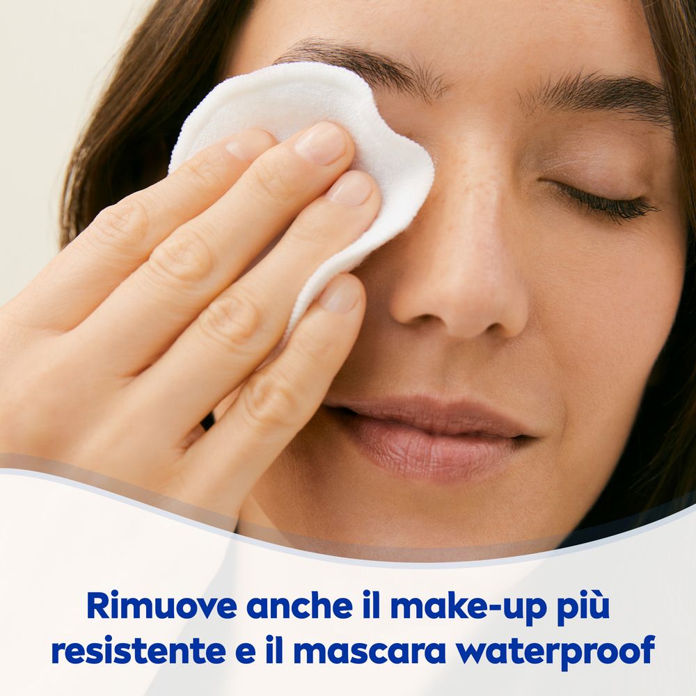 Donna che si strucca gli occhi con un dischetto di cotone. Testo: Rimove anche il make-up più resistente e il mascara waterproof.