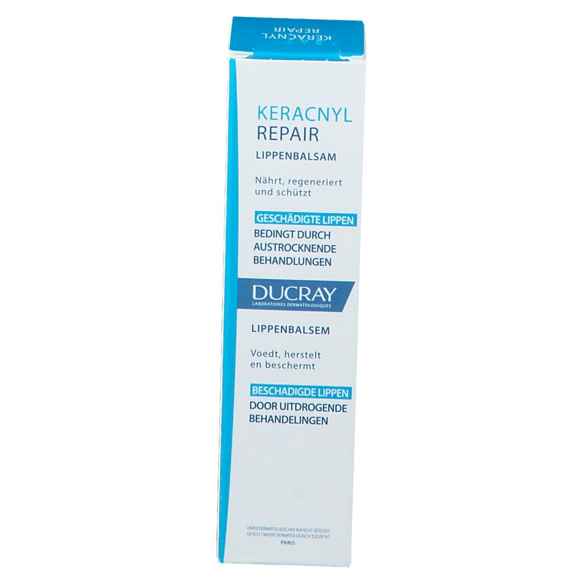 Kartonverpackung Ducray Keracnyl Repair Lippenbalsam. Weiß und blau. Text in mehreren Sprachen.