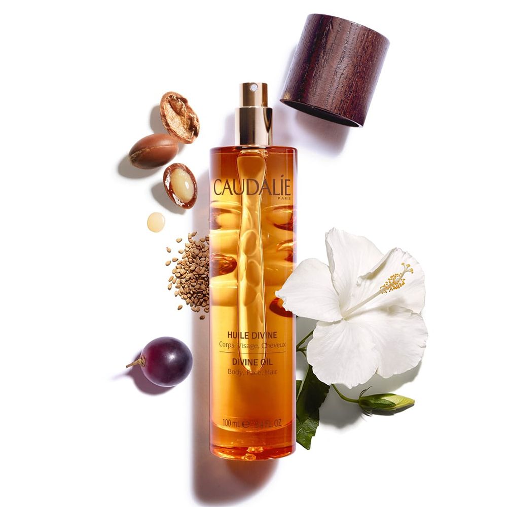 Flacon en verre ambré avec vaporisateur doré. Accompagné d'argan, raisin, sésame, fleur. Inscription CAUDALIE et HUILE DIVINE.